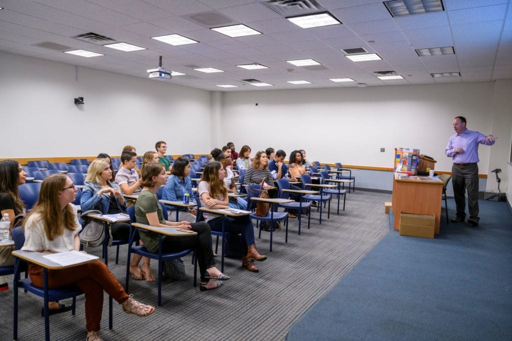 Photo of students in class and professor teaching.