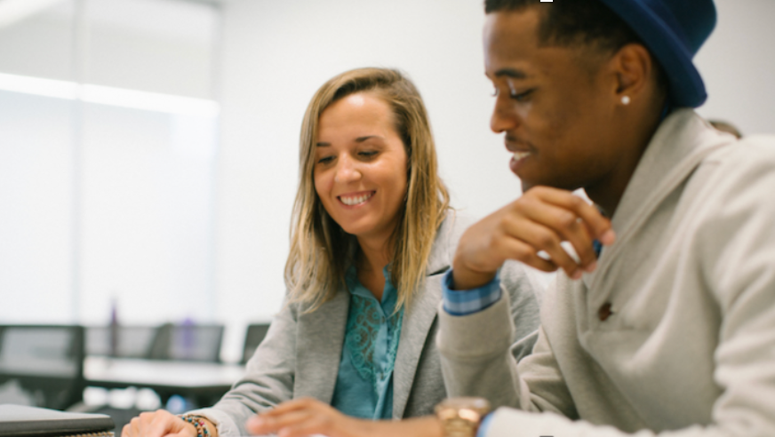 Two students sitting next to each other reviewing material